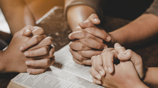 Friends praying over a Bible
