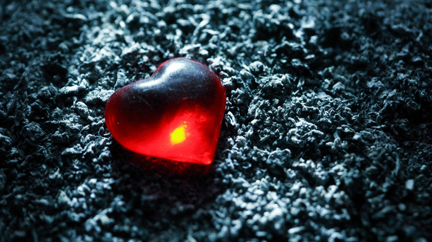 Red heart sitting on ashes
